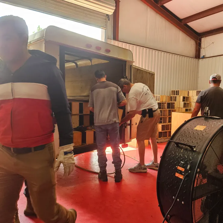 The crew loading hive boxes into a trailer in the workshop